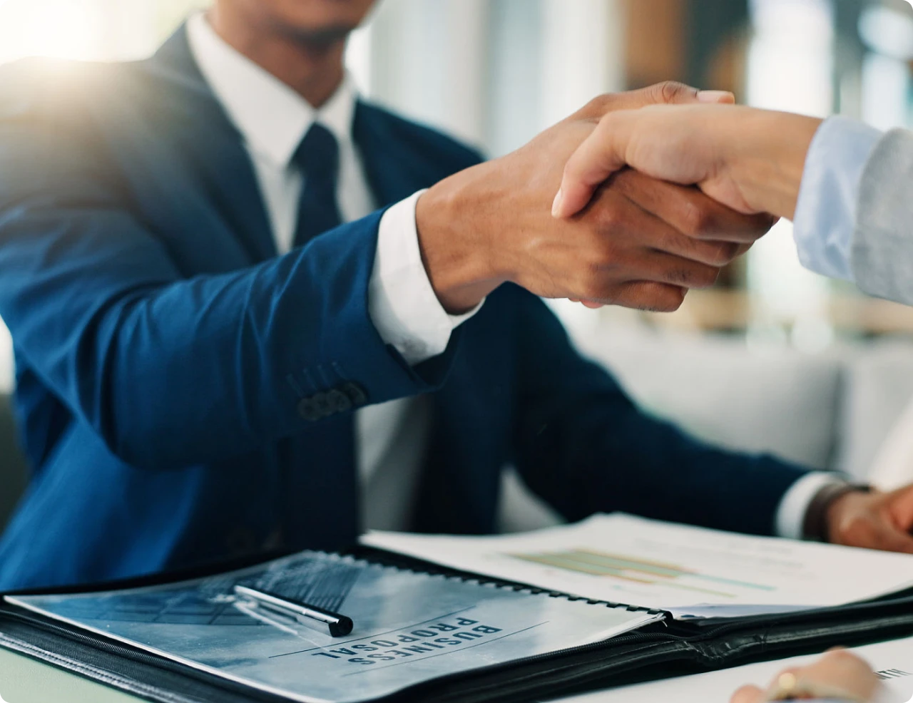 Handshake over business documents in office.